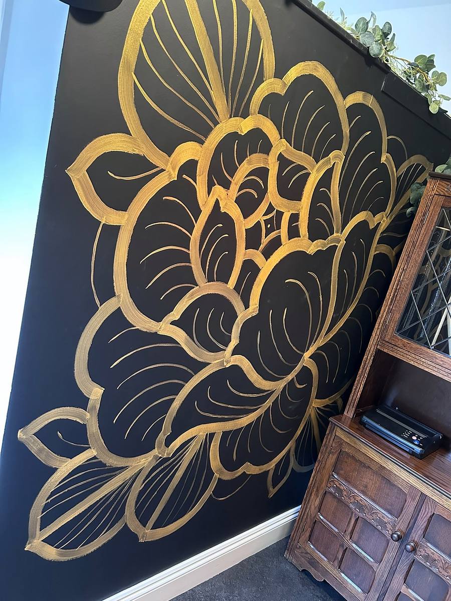 A large gold rose painted on a black wall